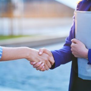 Handshake of two youngs cooperative workers outside office